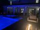 Backyard pool and spa with patio, fire pit, and string lights at night at 7702 Fairfax Dr, Kissimmee, FL 34747