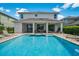 Backyard pool with a covered patio, lounging area, and lush landscaping at 7702 Fairfax Dr, Kissimmee, FL 34747