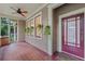 Inviting front porch boasting tile floors, ceiling fan, hanging plants, and a stylish red entry door at 803 E Harwood St, Orlando, FL 32803