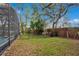 A large backyard showcasing a black metal fence, mature trees and a view of the screened pool at 827 Royalwood Ln, Oviedo, FL 32765