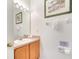 Clean bathroom with a wooden vanity, sink, toilet, and decorative beach themed artwork at 1027 Park Ridge Cir, Kissimmee, FL 34746