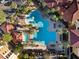 An aerial view of a resort-style pool with lounge chairs and palm trees and buildings with red tile roofs at 12521 Floridays Resort Dr # 307F, Orlando, FL 32821