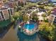 An aerial view of a community pool on a small island in a lagoon, surrounded by lush trees and beautiful buildings at 12521 Floridays Resort Dr # 307F, Orlando, FL 32821