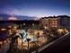 A view of a lagoon style pool surrounded by palm trees with the buildings lit up at dusk at 12521 Floridays Resort Dr # 307F, Orlando, FL 32821