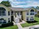 Bright yellow two-story condo with white trim, stairs, walkways, and manicured landscaping at 2040 Royal Bay Blvd # 30, Kissimmee, FL 34746