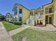 Charming yellow townhouse featuring large windows, balconies, and lush landscaping at 2040 Royal Bay Blvd # 30, Kissimmee, FL 34746