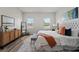 Stylish bedroom features neutral decor, light hardwood floors, and two sunny windows at 2415 Sw 165Th Pl, Ocala, FL 34473