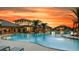 Community pool at sunset with palm tree landscaping, lounge seating, and views of the clubhouse at 2546 Empress Dr, Kissimmee, FL 34741