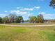 Scenic backyard view of a tranquil lake surrounded by mature trees and open green space at 27307 Pine Straw Rd, Leesburg, FL 34748