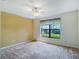 Bedroom featuring neutral carpet, ceiling fan, and a large window at 27307 Pine Straw Rd, Leesburg, FL 34748