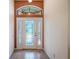Bright foyer featuring a decorative front door, transom window, and neutral tile flooring at 27307 Pine Straw Rd, Leesburg, FL 34748