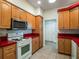 Traditional kitchen featuring warm wood cabinets, tile floors and contrasting red countertops at 27307 Pine Straw Rd, Leesburg, FL 34748