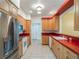 Traditional-style kitchen with wooden cabinets, stainless steel refrigerator, and contrasting red countertops at 27307 Pine Straw Rd, Leesburg, FL 34748