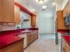 Well-lit kitchen featuring wood cabinets, red countertops, and neutral tile flooring at 27307 Pine Straw Rd, Leesburg, FL 34748