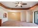 Spacious living room with neutral carpet, tray ceilings, a ceiling fan, and a view to the dining area at 27307 Pine Straw Rd, Leesburg, FL 34748