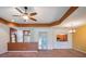 Open-concept living room with tray ceilings, neutral carpet, and views to the kitchen and back patio at 27307 Pine Straw Rd, Leesburg, FL 34748