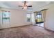 Bright main bedroom with tray ceiling, carpet, fan, and sliding glass door to lanai overlooking a view at 27307 Pine Straw Rd, Leesburg, FL 34748