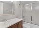 Bright bathroom features a wood vanity cabinet, framed mirror and bathtub with sliding glass door at 3801 S Atlantic Ave # 105, New Smyrna Beach, FL 32169