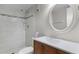 Bathroom features a tiled shower and a sink with a round mirror in this compact space at 3801 S Atlantic Ave # 105, New Smyrna Beach, FL 32169