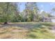 Expansive backyard with mature trees and a view of the pool enclosure, offering privacy at 388 Nowell Loop, Deland, FL 32724