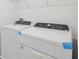 Modern white washer and dryer set with overhead storage shelf in laundry room at 4369 Switchgrass Ln, St Cloud, FL 34772