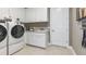 Functional laundry room with modern washer and dryer, ample storage, and a utility sink at 5641 Nevis Ter, Kissimmee, FL 34758
