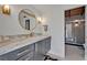 Modern bathroom featuring a round mirror, marble countertop, and tiled shower stall with a patterned wall at 605 Sweetbriar Rd, Orlando, FL 32806