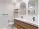 Stylish bathroom with dual sinks, wood cabinets, and sleek arched mirrors at 660 Celebration Ave # 220, Celebration, FL 34747
