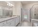 Bright bathroom with granite countertops, double vanity, and a glass-enclosed shower, offering modern comfort and style at 7180 Oakmoss Loop, Davenport, FL 33837