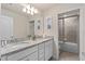 Well-lit bathroom with double vanity, granite countertops, and glass enclosed shower/tub is modern and functional at 7180 Oakmoss Loop, Davenport, FL 33837