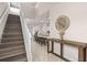 Bright foyer with staircase, table, mirror, and an open view into the kitchen and living area at 7180 Oakmoss Loop, Davenport, FL 33837