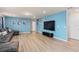 Bright living room with eye catching blue accent wall, large TV and comfy sectional is the perfect hangout at 7180 Oakmoss Loop, Davenport, FL 33837