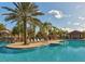 Gorgeous swimming pool with sun loungers, lush landscaping, and swaying palm trees on a sunny day at 7180 Oakmoss Loop, Davenport, FL 33837