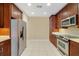 Modern kitchen with stainless steel appliances, wood cabinets and tile floors at 7508 Toscana Blvd # 123, Orlando, FL 32819