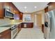 Modern kitchen with stainless steel appliances, tile floor, wood cabinets, and granite counters at 7508 Toscana Blvd # 123, Orlando, FL 32819
