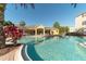 A community pool with a yellow clubhouse and lounge chairs for relaxing by the water in the Florida sun at 8124 Claire Ann Dr # 303, Orlando, FL 32825