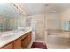 Bathroom featuring double sinks, walk-in shower and separate soaking tub with tile surround at 10033 Hidden Dunes Ln, Orlando, FL 32832