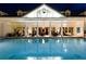 Swimming pool at night, reflecting the clubhouse, with chairs and tables around the building at 1004 Castle Pines Ct, Reunion, FL 34747