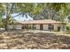 Single-story home featuring a covered front porch with wooden pillars, a manicured lawn, and mature trees at 1035 W Minnehaha Ave, Clermont, FL 34711