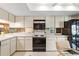 Bright kitchen featuring white cabinets, black appliances, and mirrored backsplash for a modern look at 1055 Kensington Park Dr # 609, Altamonte Springs, FL 32714