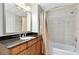 Bathroom with wood cabinets, granite counters, a tiled shower and tub, and a decorative mirror at 1360 Centre Court Ridge Dr # 201, Reunion, FL 34747