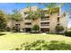 Multi-story building with balconies, set among palm trees, and a lush green lawn on a bright, sunny day at 1360 Centre Court Ridge Dr # 201, Reunion, FL 34747