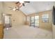 Bright living room with carpet, vaulted ceiling, fan, and sliding glass doors leading to an enclosed patio at 154 Pecan Dr, Ocala, FL 34472