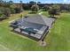 Elevated view of a private pool and home with screened enclosure, nestled on an expansive lot with mature trees and green space at 15523 Trotting Horse Ln, Tavares, FL 32778