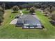 Stunning aerial perspective showcasing a home with a screened-in pool, surrounded by vast green lawns and mature trees at 15523 Trotting Horse Ln, Tavares, FL 32778