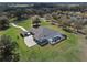 Expansive aerial view of a luxurious home with a screened pool, manicured lawn, and a long, winding driveway amidst lush greenery at 15523 Trotting Horse Ln, Tavares, FL 32778