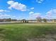 Expansive backyard view featuring a well-maintained lawn, a serene pond, mature trees, and a classic white fence at 15523 Trotting Horse Ln, Tavares, FL 32778
