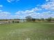 Expansive backyard view featuring a well-maintained lawn, a serene pond, mature trees, and a classic white fence at 15523 Trotting Horse Ln, Tavares, FL 32778