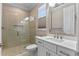 Modern bathroom featuring a walk-in shower with glass doors, and a white vanity with quartz countertop at 15523 Trotting Horse Ln, Tavares, FL 32778