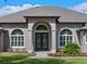 Close-up of the front entrance showcasing elegant double doors framed by arched windows and lush landscaping at 15523 Trotting Horse Ln, Tavares, FL 32778